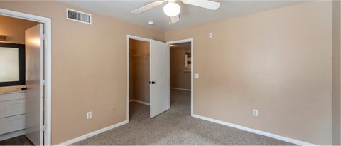 A room with a ceiling fan and a mirror on the wall.